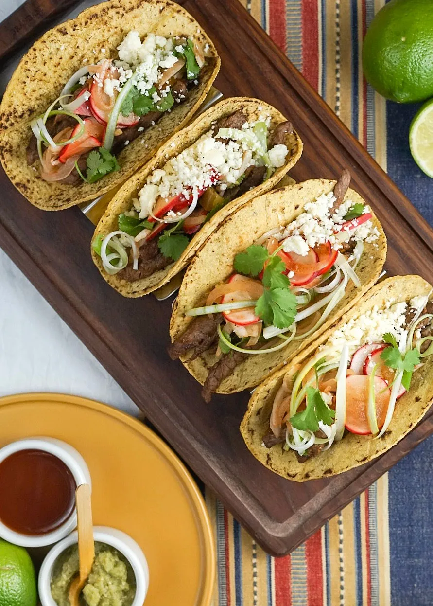 Grilled steak tacos on warm stone-ground corn tortillas, finished with fresh herbs and crunch