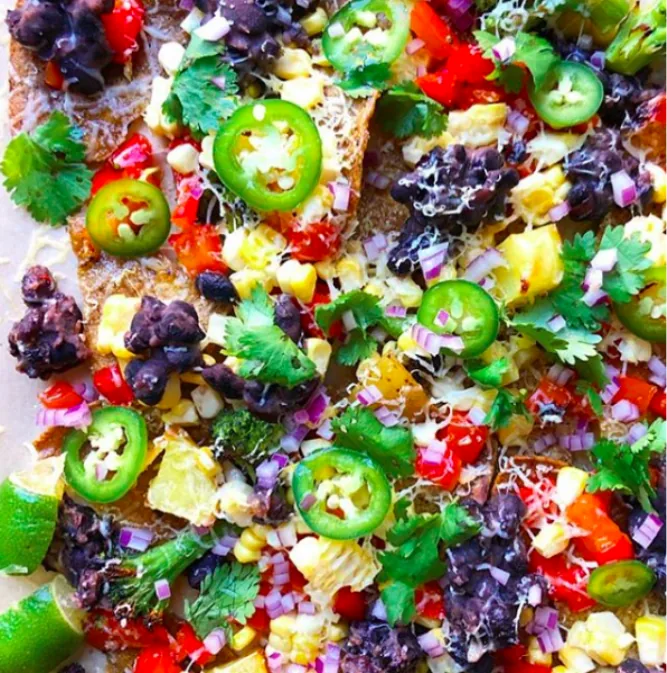 Loaded corn tortilla nachos with black beans, corn kernels, red peppers, red onion, jalapeño and cilantro