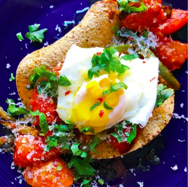 Open corn tortilla with seared tomatoes, jalapeño, grated cheddar, fresh herbs and a poached egg