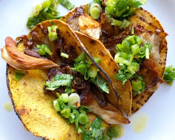 Corn tortilla filled with roasted mushrooms and topped with sliced scallions
