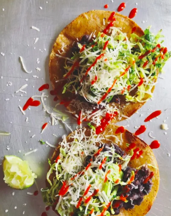 Crisp corn tostadas layered with black beans, finely shaved Brussels sprouts, grated white cheddar and hot sauce