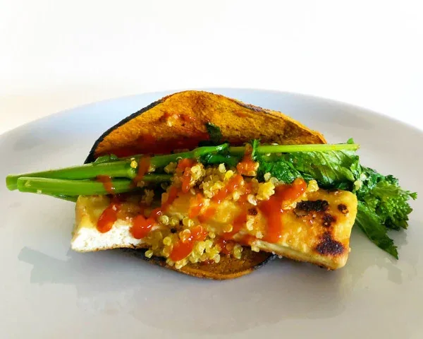 A folded street taco with colorful vegetable fillings