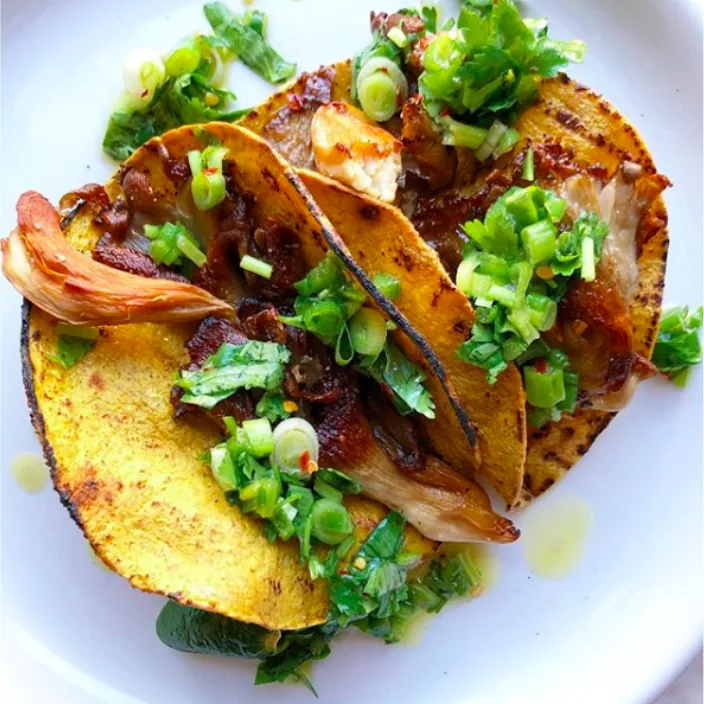 Corn tortillas filled with browned oyster mushrooms and chopped scallion and cilantro salsa