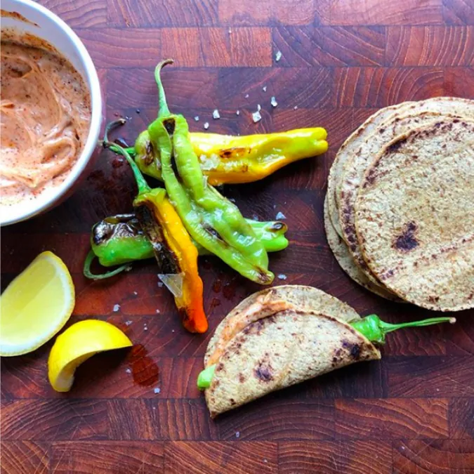 Blistered shishito peppers with small corn tortillas, lemon wedges and a bowl of chili mayonnaise