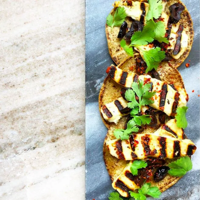 Small corn tortillas topped with grill-marked halloumi strips, chopped black olives, cilantro and chili flakes