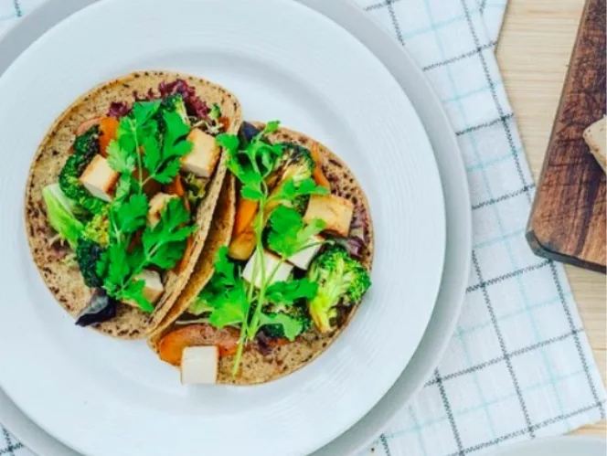 Corn tacos filled with tofu cubes, broccoli, sliced carrot and fresh cilantro