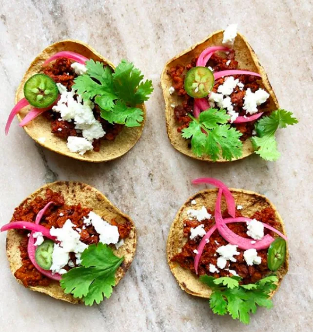 Corn tortilla tacos topped with browned chorizo, pickled red onion, jalapeño rings, crumbled cotija and cilantro