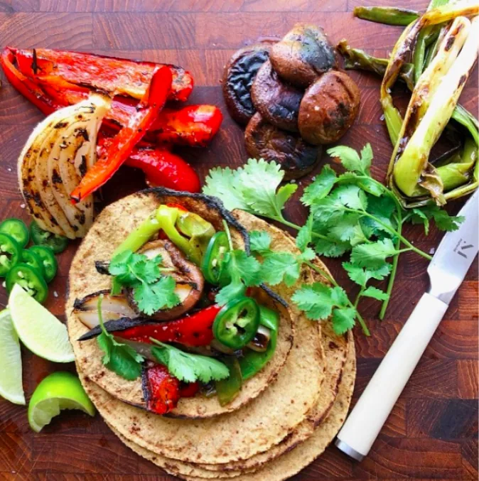 Grilled peppers, onion wedges, mushrooms and scallions alongside corn tortillas, cilantro, jalapeño and lime