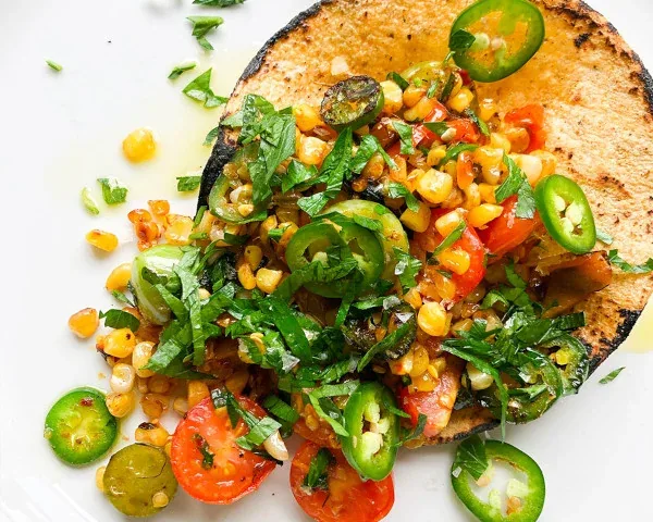 Street taco topped with corn and sliced peppers