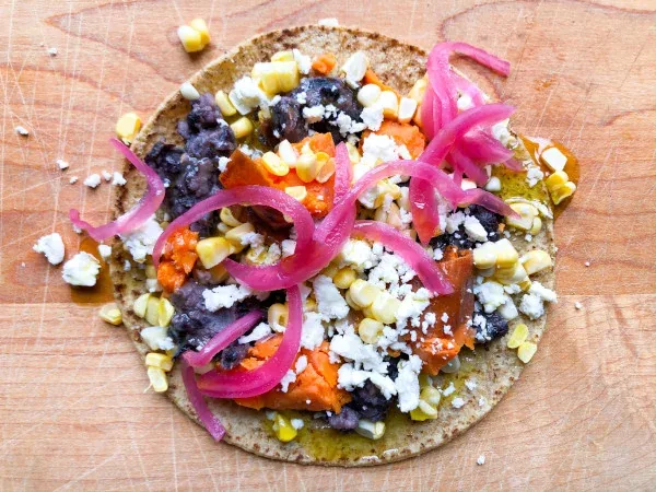 Street taco with vegetables, beans, and pickled onions