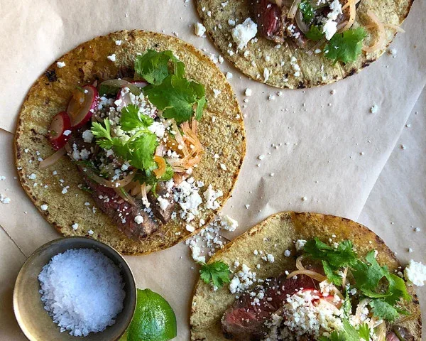 Corn tortillas topped with beans, cilantro, and crumbled cheese