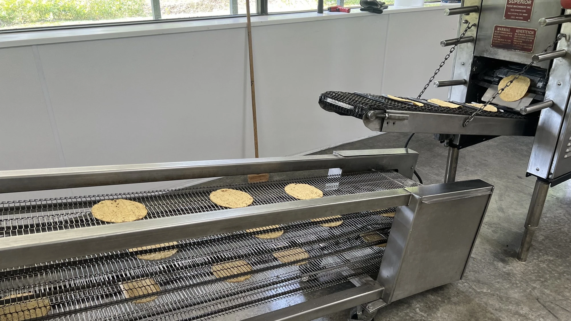 Corn tortillas moving through the oven and along conveyor belts at Vermont Tortilla Company.